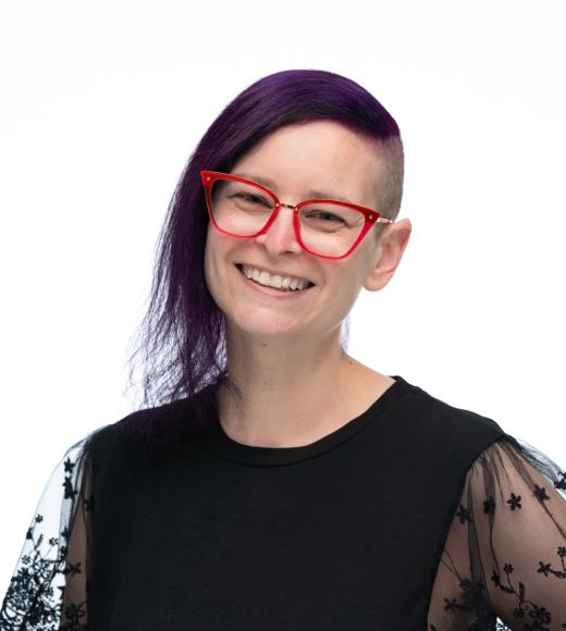 Headshot of Jennifer wearing a black shirt and pink glasses