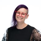 Headshot of Jennifer wearing a black shirt and pink glasses