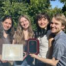Photo of Joss Greene with three students posing with an award plaque