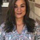 Headshot of Ariana Valle wearing a pastel-print top and shoulder-length, brown hair with a side part.