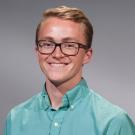 Headshot of Patrick Wade in a turquoise button down against a gray background
