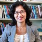 Headshot of Ming-Cheng Lo in a gray blazer and books in the background. 